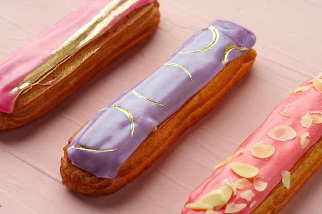 Photo eclair dessert with icing on pink wooden background