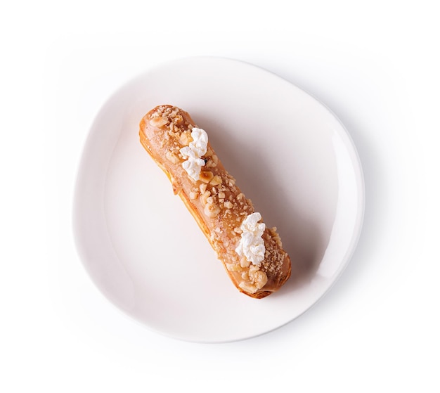 Eclair with caramel and nuts on white plate