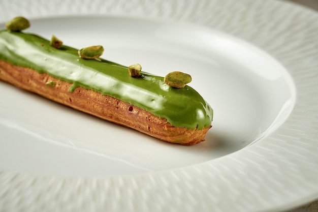 Eclair with pistachio glaze on a plate Noise added in postproduction Selective focus