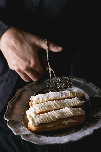 Eclairs on metal plate in woman's hands