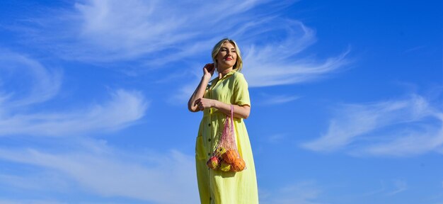 Eco aware Woman carry fruits and vegetables in eco bag Zero waste Plastic free concept Sustainable lifestyle Reusable cotton and mesh eco bags for shopping Girl summer day blue sky background