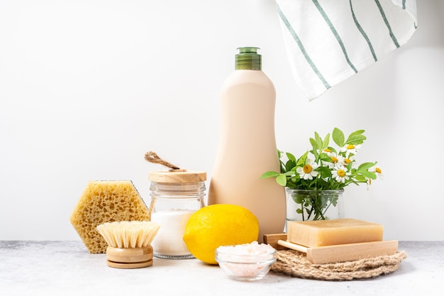 Eco friendly natural cleaners jar with baking soda dish brush lemon flowers soap on white background