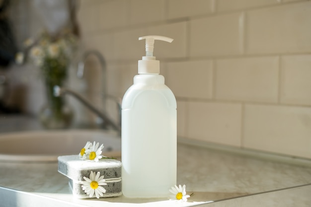 Eco friendly non-toxic cleaning dish soap with chamomile flowers, clean white plates . High quality photo