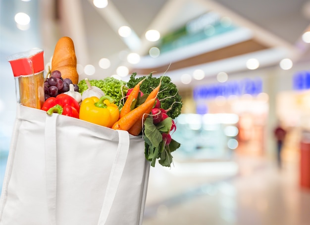 Eco friendly reusable shopping bag filled with vegetables on a blur background