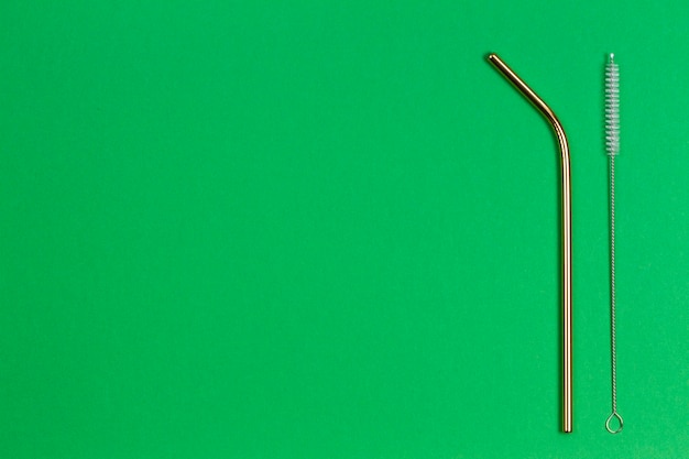 Eco friendly stainless steel reusable drinking straw and cleaning brush on green background