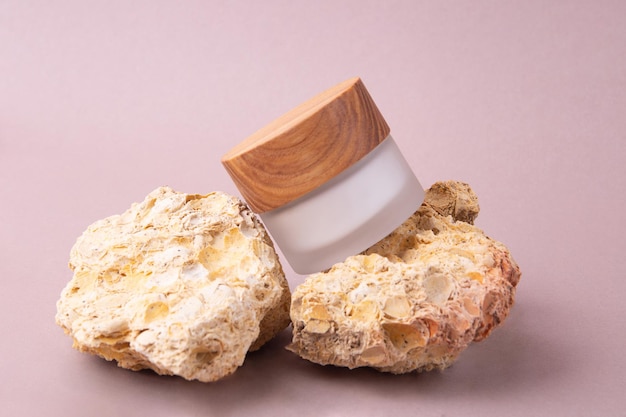 Eco friendly white cream container with wooden cover on the natural stonesGood as cosmetics mockup