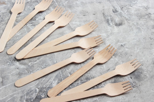 eco-friendly wooden forks on gray concrete background.