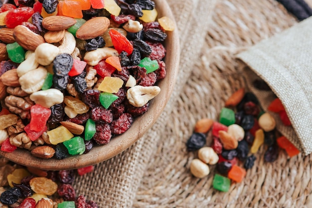 Eco sack with candied fruits spilling out and wooden plate with dried fruits on the table