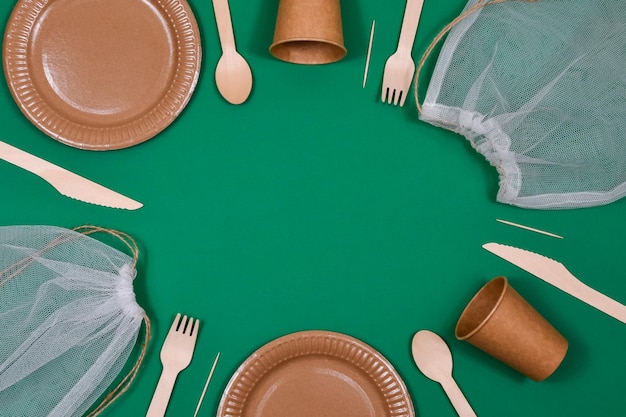 Ecofriendly disposable cardboard paper utensils on a green background Place for an inscription