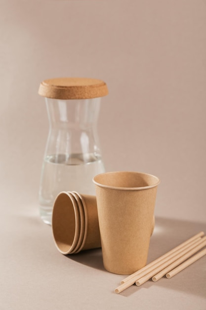 Ecofriendly disposable utensils made of craft paper on a light beige background Paper cups and straws