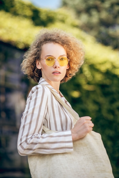 Ecological issues. Young woman in sunglasses in the street with eco bag in hands