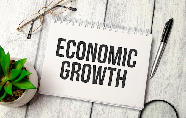 ECONOMIC GROWTH text on a notepad with pen glasses and plant