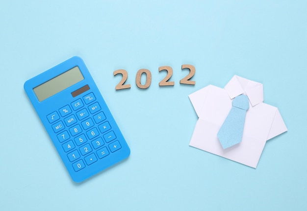 Economic plan business concept Calculator origami shirt with tie and 2022 on blue background