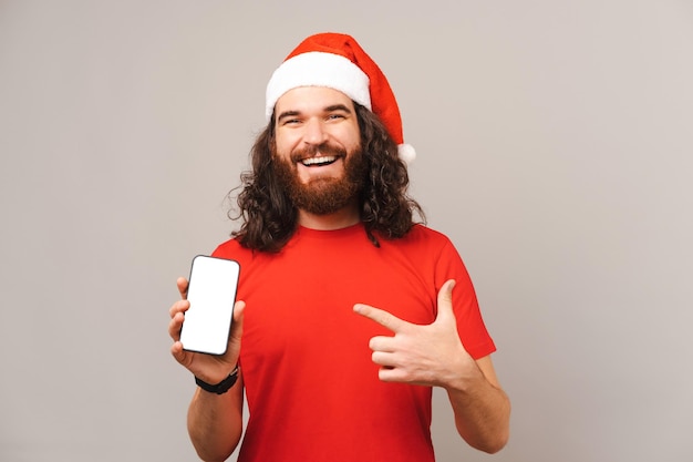 Ecstatic bearded Christmas man is showing phone screen and pointing at it