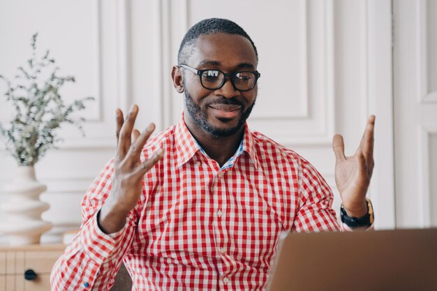 Ecstatic black man in glasses reading laptop news celebrates office success a joyful African employee