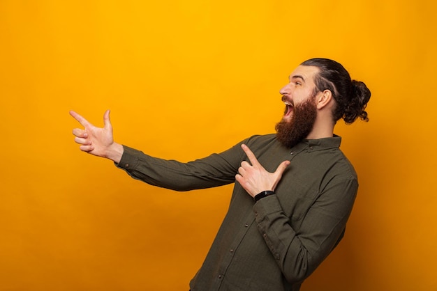 Ecstatic man is pointing aside with both hands while screaming of joy