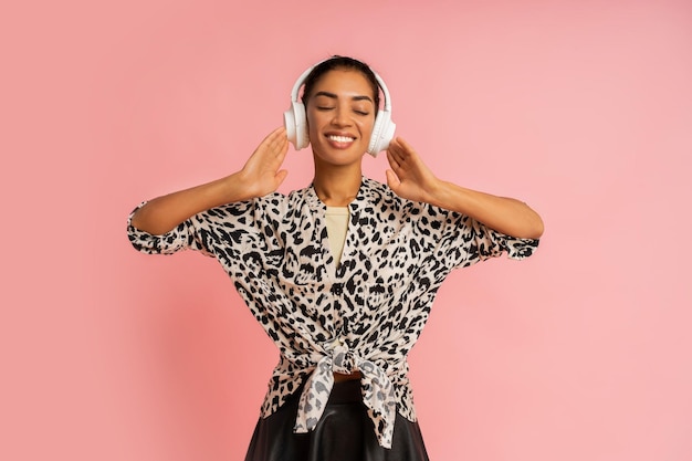 Ecstatic woman enjoing lovely music on pink background