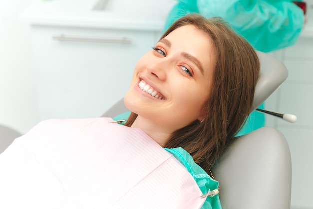 Ecstatic young woman is wide smiling while sitting on the dentist chair Close up photo with copy space