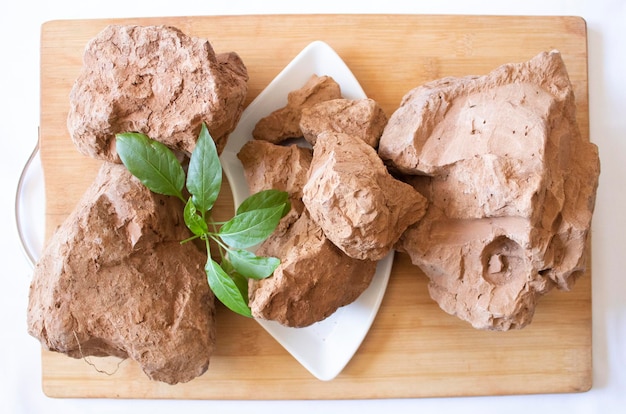 Edible brown clay stones with green leaves on a white background