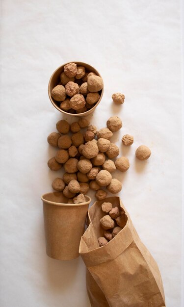 Edible caramel clay stones in brown bag and cups on a white background