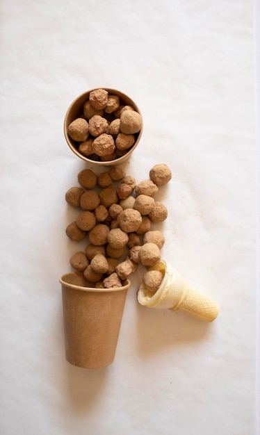 Edible caramel clay stones in brown bags with an icecream cone on a white background