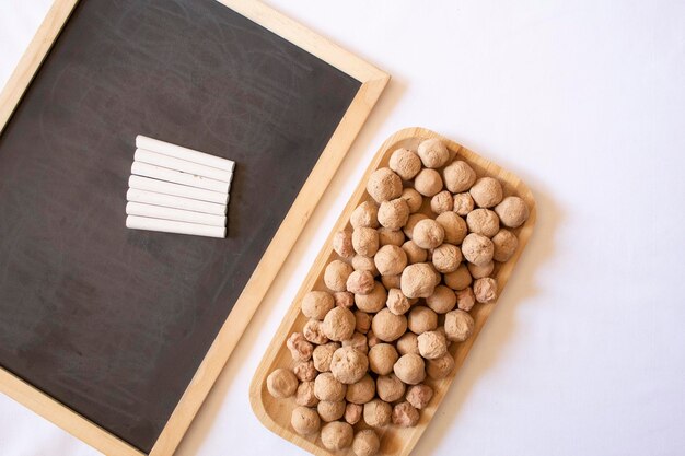 Edible caramel clay stones on a wooden plate next to a chalk board with white chalks flat lay