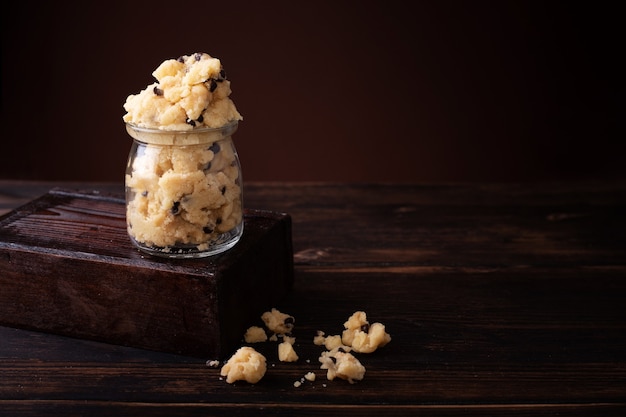 Edible cookie dough in glass jar on the dark wooden table