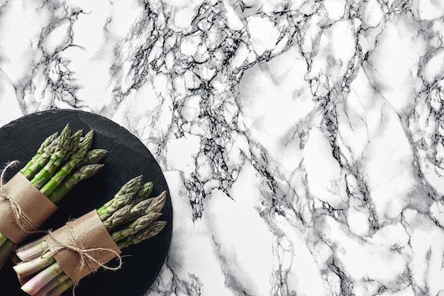 Photo an edible raw stems of asparagus on a marble background