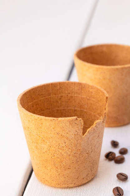 Edible waffle coffee cups with roasted coffee beans on white wooden table zero waste concept