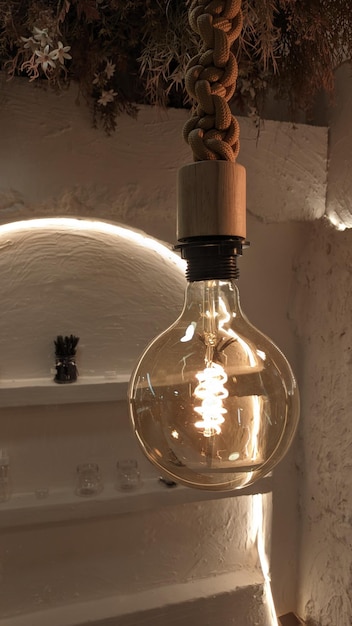 Edison's electric decorative lamp burns in the house near the wall with shelves