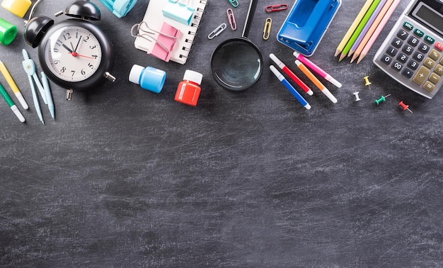 Education or back to school Concept Top view of Colorful school supplies with books color pencils calculator pen cutter and clips on backboard background