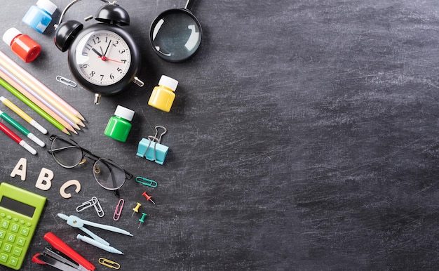 Education or back to school Concept Top view of Colorful school supplies with books color pencils calculator pen cutter and clips on backboard background