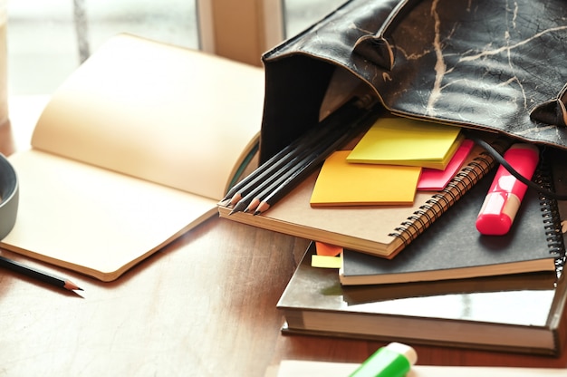 Education concept, Bag with book, notebook, pencil and pen marker with sticky note on table.