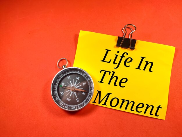 Education conceptText Life in the moment on colorful paper note with compass on red background