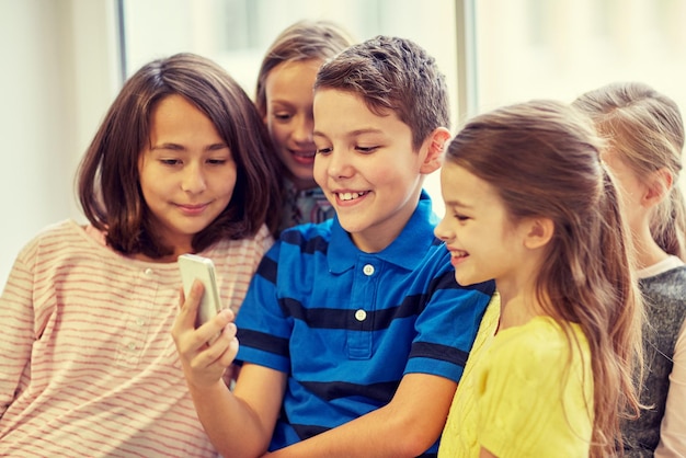 education, elementary school, drinks, children and people concept - group of school kids taking selfie with smartphone in corridor