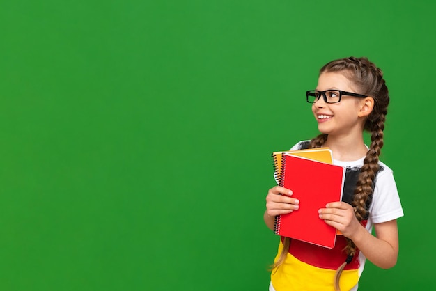 Education in Germany for children A little girl with a German flag and notebooks on a green isolated background Learning foreign languages Copy space