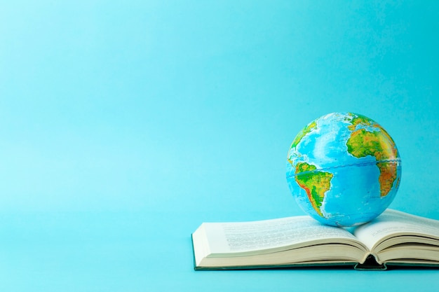 Education and globalism concept. Globe on an open book on a table in a university class on a blue background