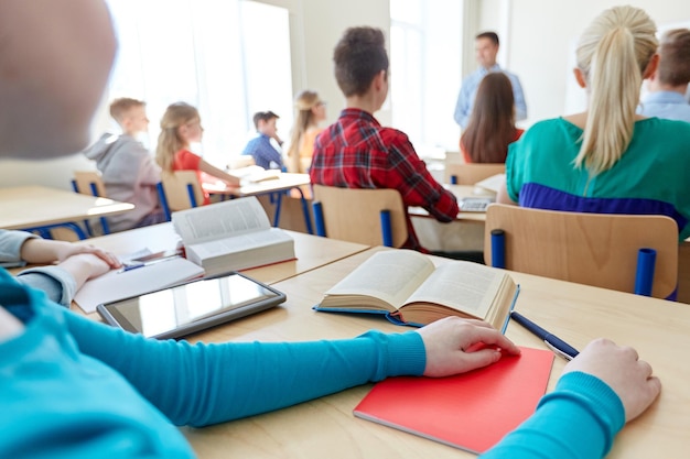 education, high school, learning and people concept - group of students listening to teacher at lesson