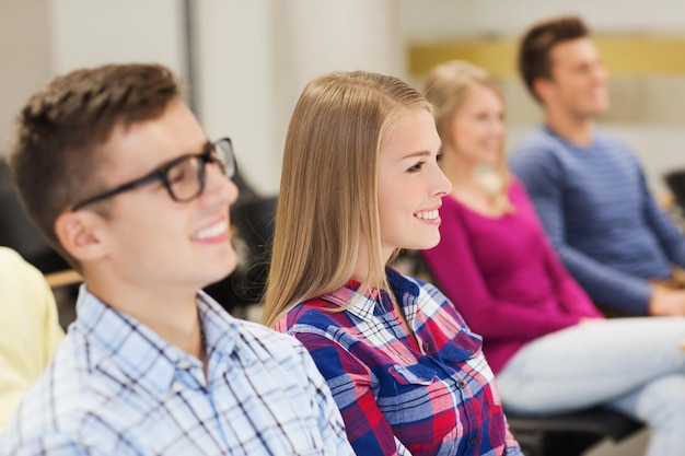 education, high school, teamwork and people concept - group of smiling students sitting in lecture hall