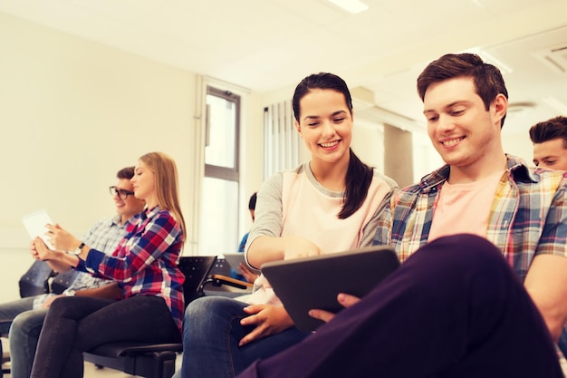 education, high school, teamwork and people concept - group of smiling students with tablet pc computers sitting in lecture hall