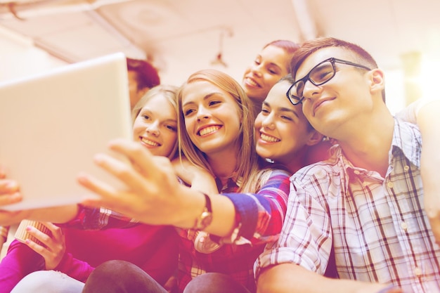 education, high school, technology and people concept - group of smiling students with tablet pc computer taking photo or video indoors