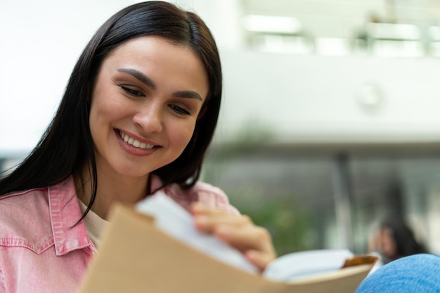 Education high school university learning and people concept Portrait view of the smiling caucasian student girl reading book at library