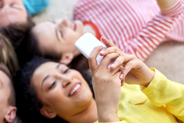 education, people and technology concept - close up of students  or friends with smartphones lying on floor in circle