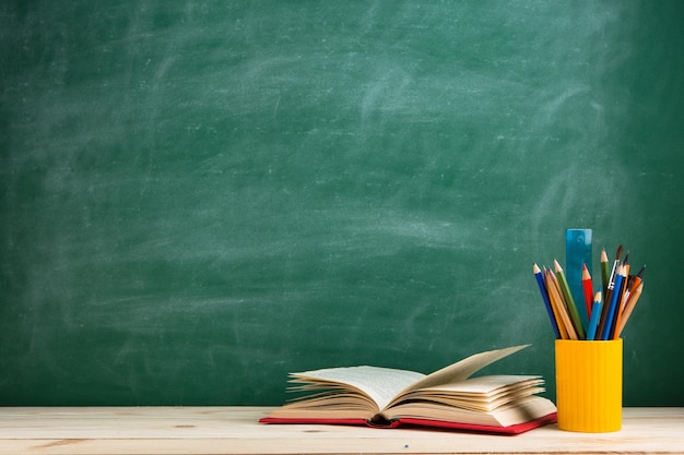 Education and reading concept group of colorful books on the wooden table in the classroom blackboard background