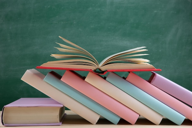 Education and reading concept group of colorful books on the wooden table in the classroom blackboard background