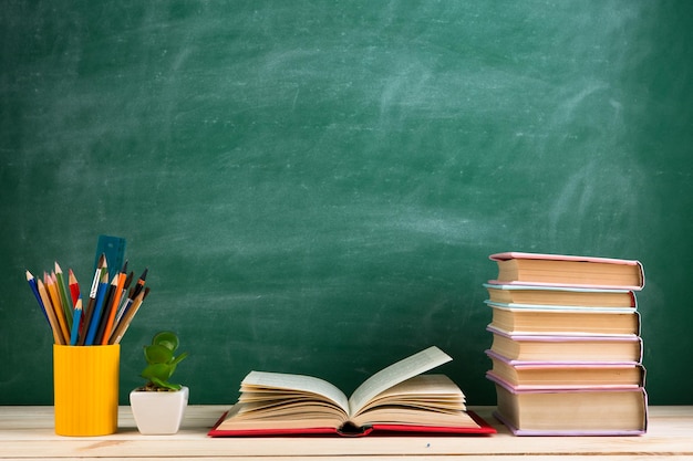 Education and reading concept group of colorful books on the wooden table in the classroom blackboard background