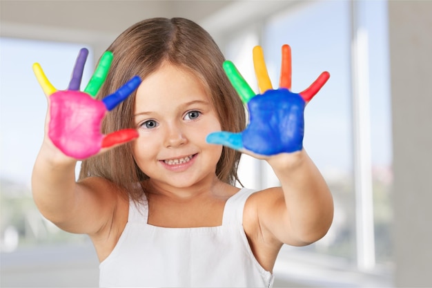 education, school, art and painitng concept - little student girl showing painted hands at school