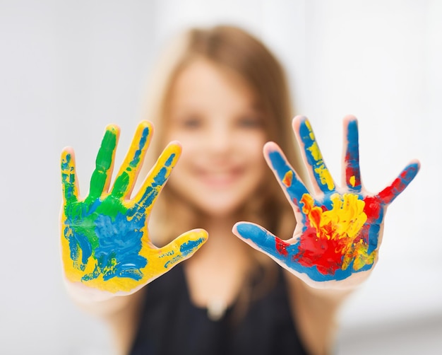 education, school, art and painitng concept - little student girl showing painted hands