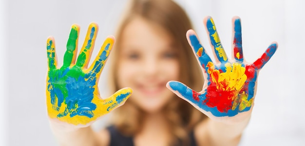 education, school, art and painitng concept - little student girl showing painted hands