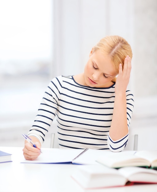 education, school and business concept - concentrated woman with books and notebook studying in college